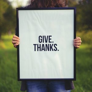 person holding rectangular black wooden photo frame with Give. Thanks. print