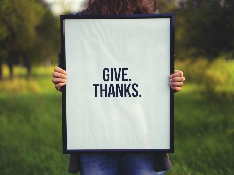 person holding rectangular black wooden photo frame with Give. Thanks. print
